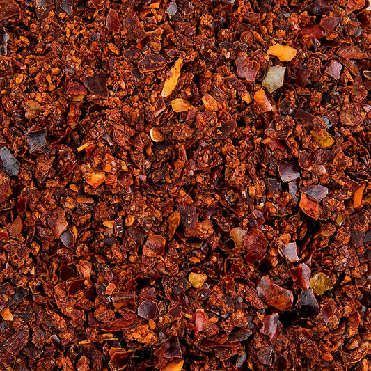 Bild eines Kilogramms geschrotetem, mildem Chili mit einer Körnung von 2-4 mm, das fruchtig nach Paprika schmeckt und eine milde Schärfe aufweist Geeignet für Soßen, Eintöpfe, Fleischgerichte, Pizza und Gemüse Ideal auch für die Herstellung eigener Gewürzmischungen